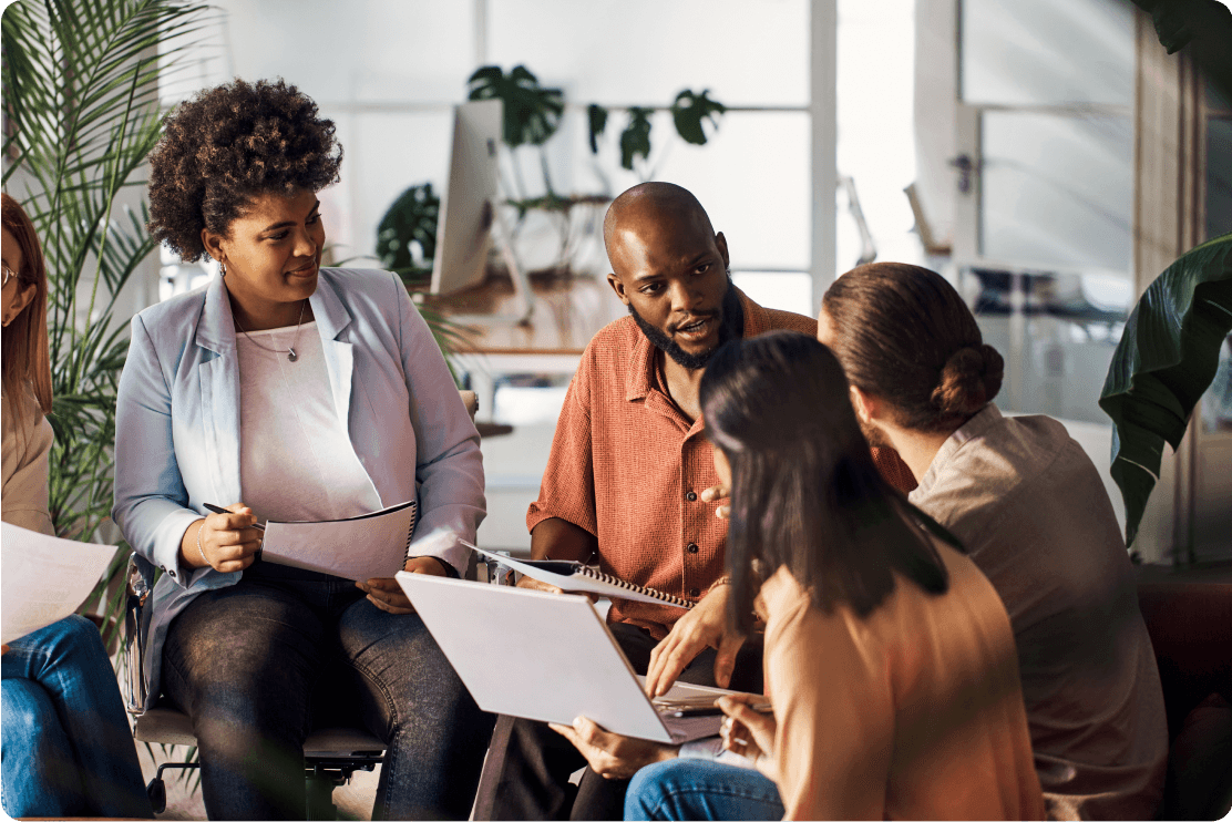 Group of people talking looking through notebooks and laptops